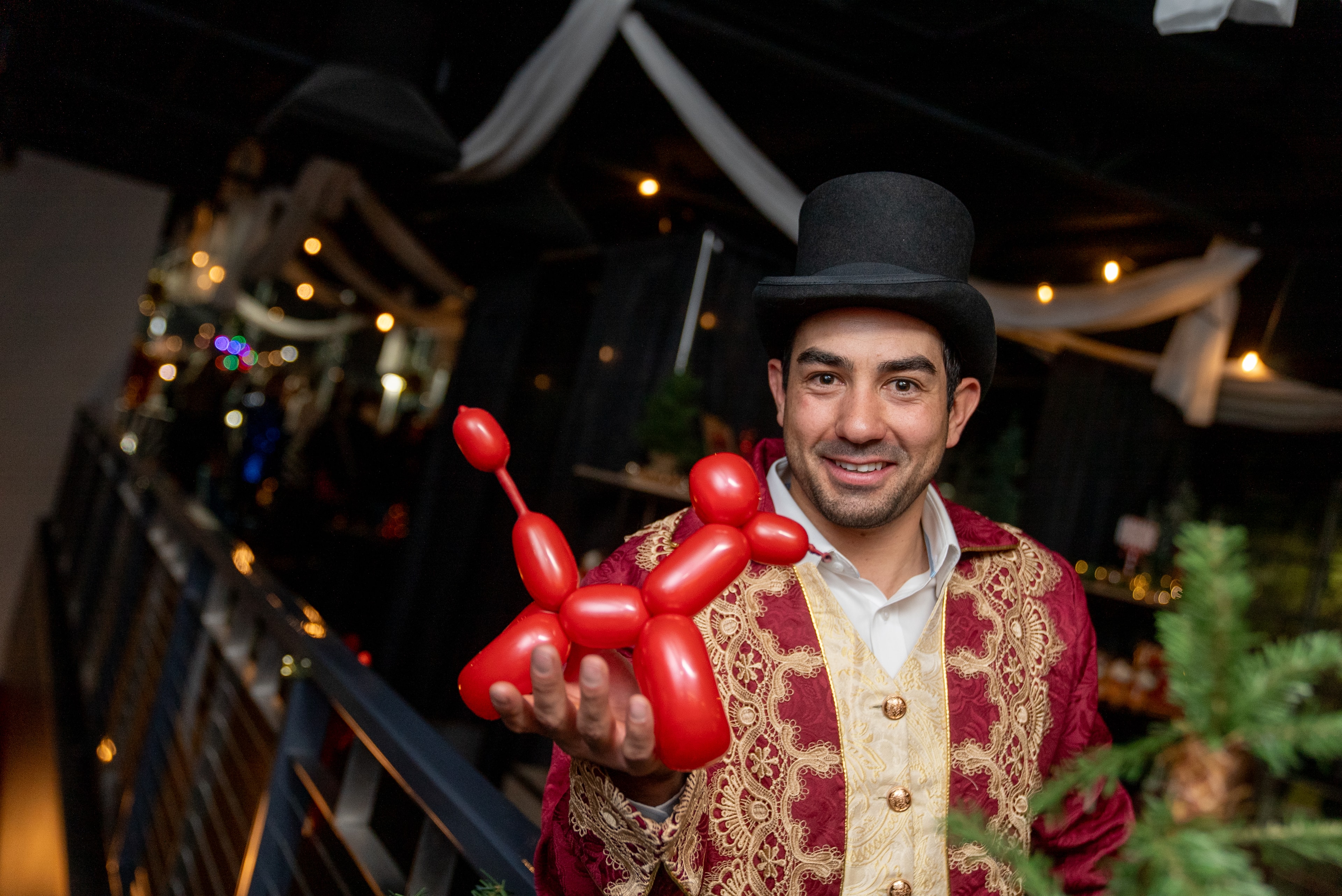 Man in top hat holding red balloon dog
