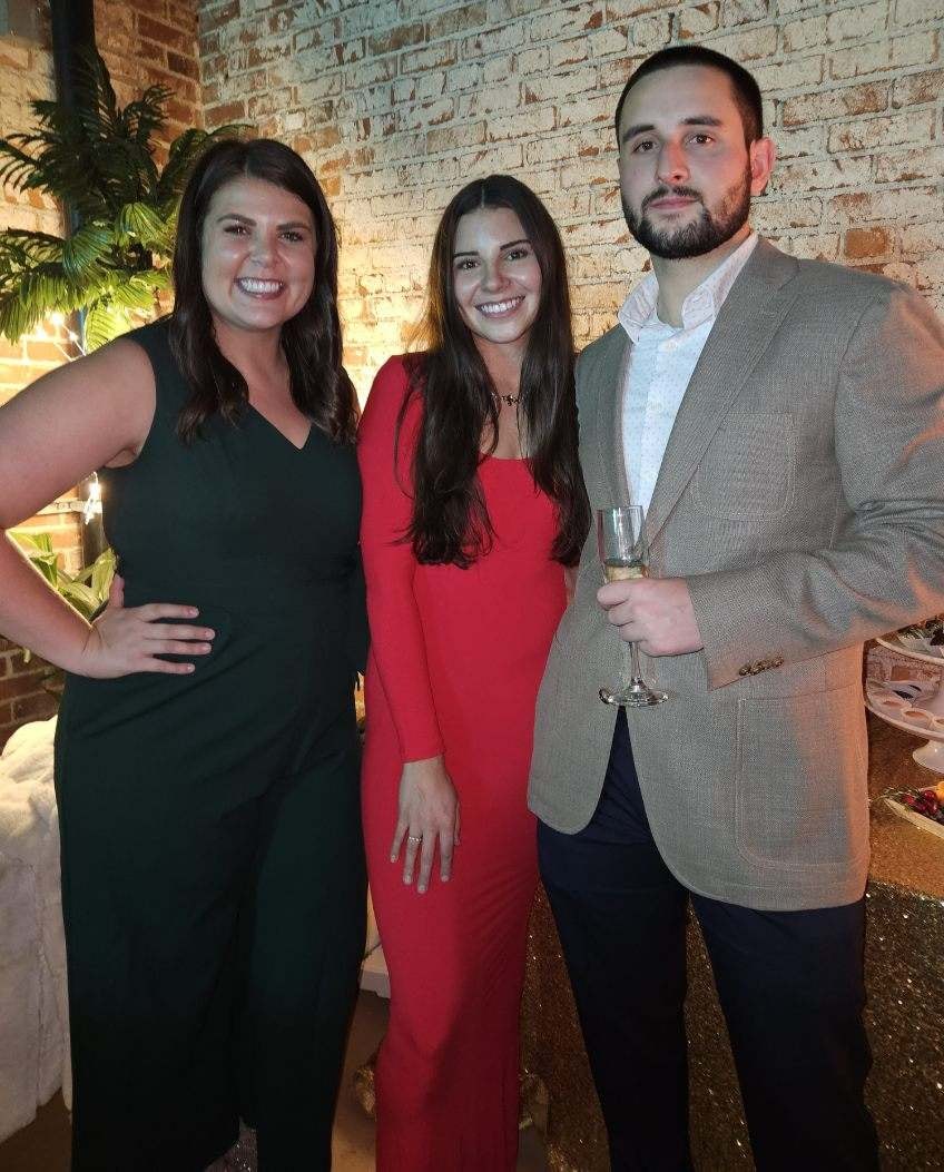 Three people posing at formal event